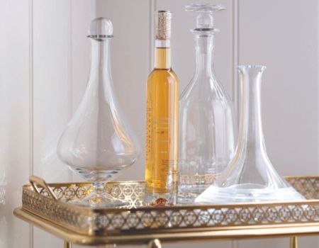 A bottle of Frank Family’s Late Harvest Chardonnay placed on a bar cart with 3 decanters 