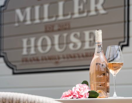 A bottle of Frank Family's Leslie Rosé and wine glass in front of Miller House sign
