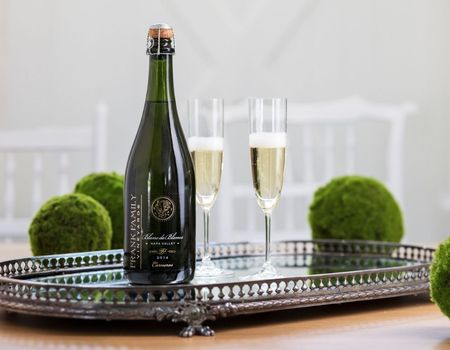 a bottle of Frank Family’s Blanc de Blancs on a table besides two wine glasses