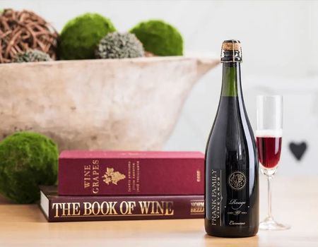 A bottle of Frank Family's Rouge with two wine glasses and two book