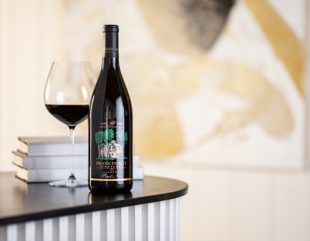 A bottle of Frank Family's Carneros Pinot Noir with a wine glass in front of a painting
