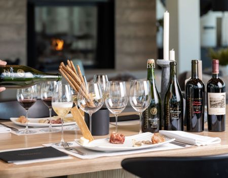 A guest swirling their wine glass beside a plate of artisanal cheeses and meats