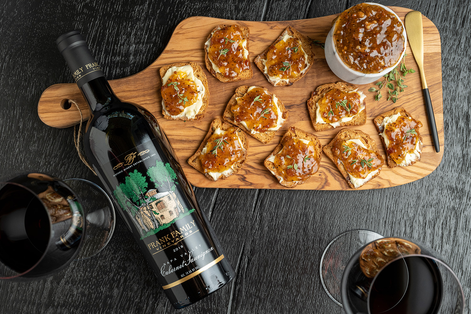Crostini with bacon jam, a bottle of Frank Family's Napa Valley Cabernet Sauvignon, and a wine glass