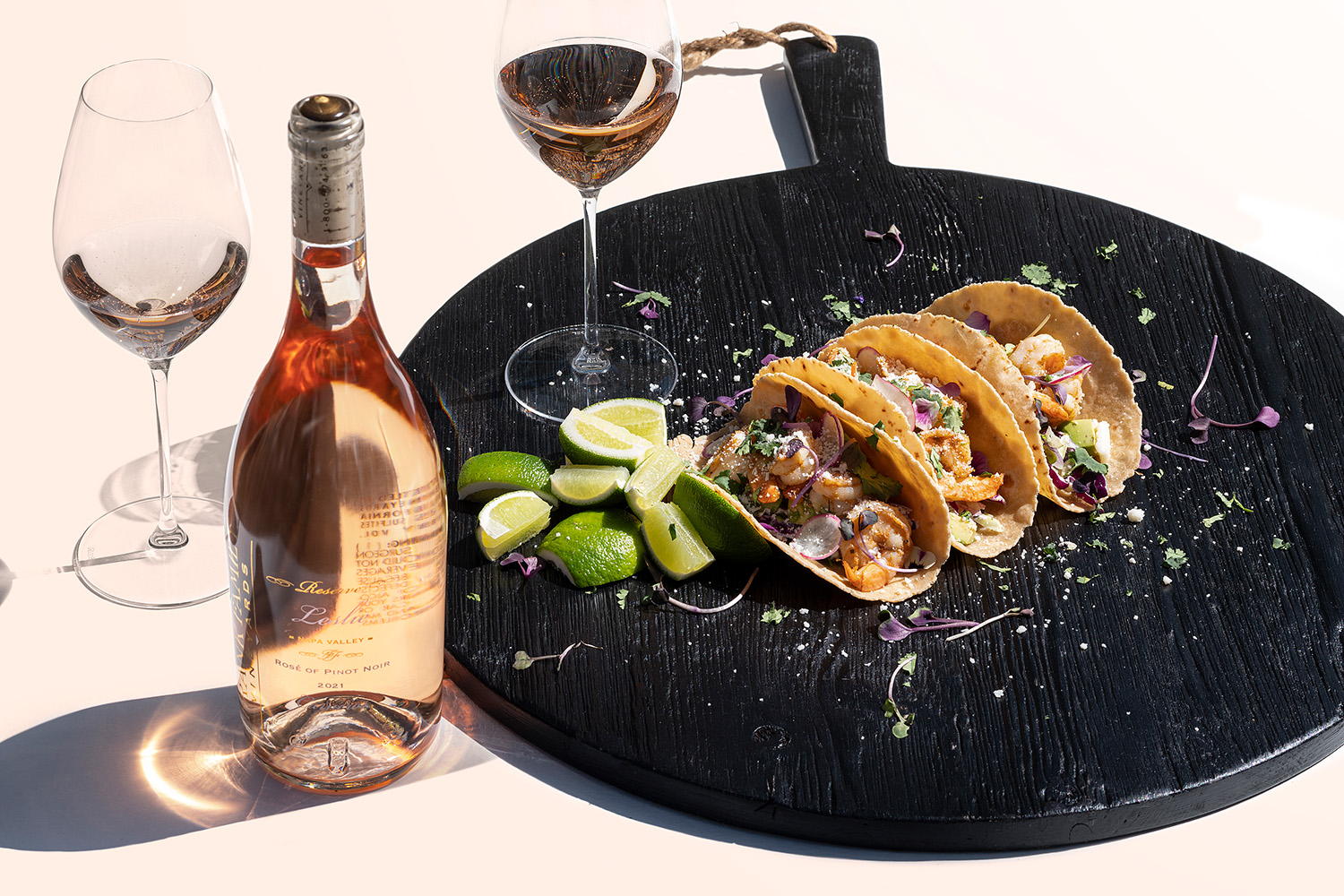 A bottle of Frank Family's Leslie Rosé next to a wine glass and plate of shrimp tacos