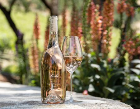 A bottle of Leslie Rosé and wine glass set against some flowers
