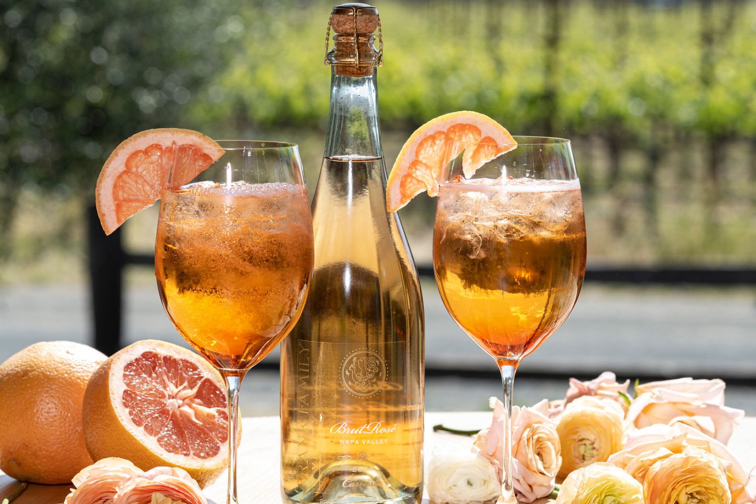 two glasses of aperol spritz next to a bottle of brut rosé