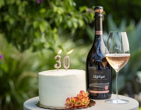 A bottle of Frank Family's 30th Anniversary Lady Edythe Brut Rosé paired with a cake lit up with 30 candles