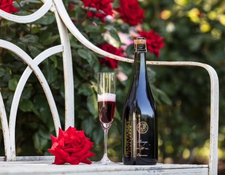 A bottle of sparkling Rouge sitting on a bench in a rose garden