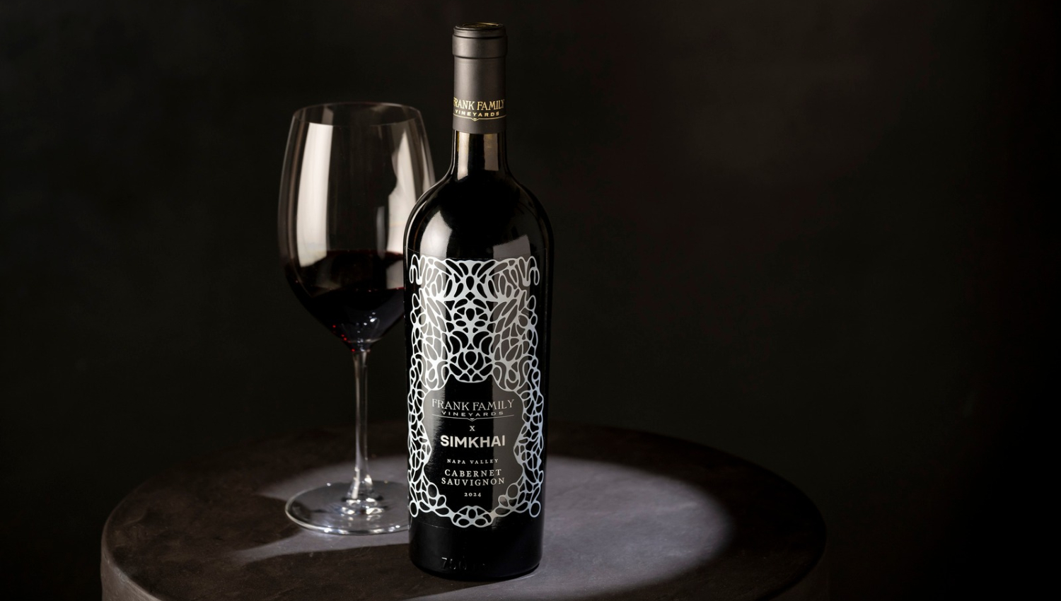 Frank Family Vineyards x SIMKHAI Custom Cabernet bottle and glass on a black background 