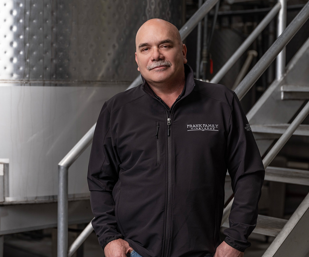 Armando pauses for a picture along side a wine fermenter