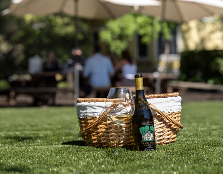 A picnic basket with a bottle of Frank Family Chardonnay in the sun