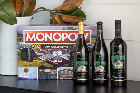 Three bottles of Frank Family wine next to the new Monopoly Napa Valley game board